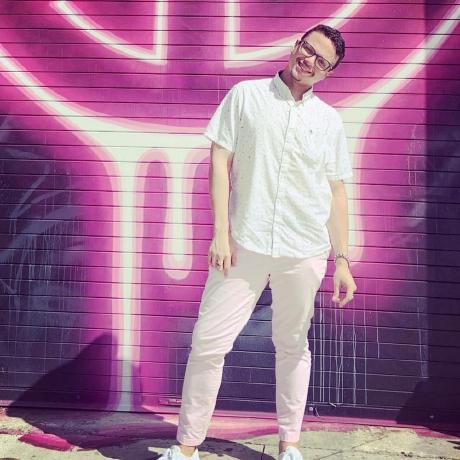 Cris Santiago standing in front of a vivid mural